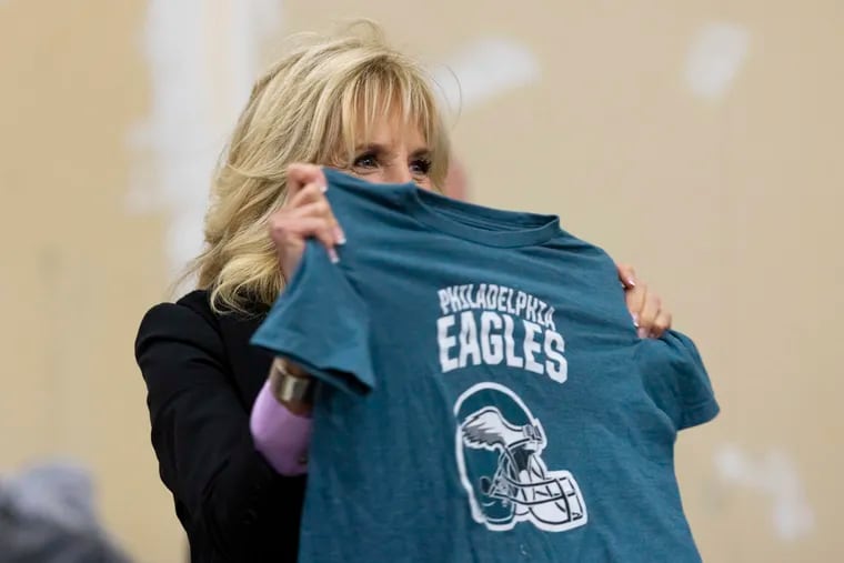 First lady Jill Biden holds up a Philadelphia Eagles shirt while sorting children's clothes at the FEMA State Disaster Recovery Center in Bowling Green, Ky., Friday, Jan. 14, 2022. Bowling Green was one of several areas hard hit by Dec. 10 tornadoes that tore through the western part of Kentucky. (AP Photo/Michael Clubb)