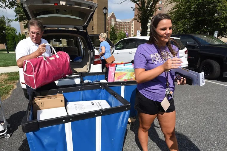 West Chester University freshman Maddie Weaver, right, with assistance from her father Ron Weaver, left. and mom Kathe Weaver, center, move into her campus dorm Monday Aug. 23, 2021.