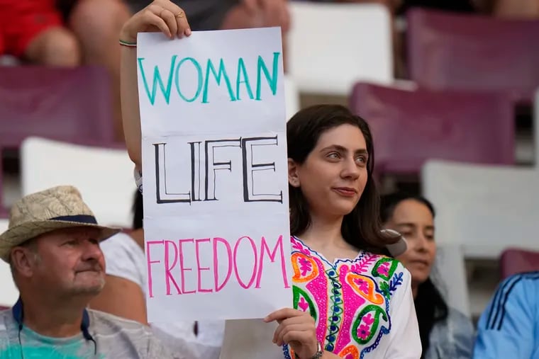 A woman holds up sign reading Woman Life Freedom, prior to the World Cup group B soccer match between England and Iran at the Khalifa International Stadium in in Doha, Qatar, Monday, Nov. 21, 2022.