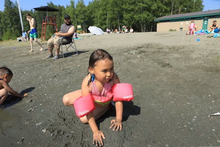 Milana Acuna, 5, makes a mud creation at the beach at Goose Lake as her father, Manny Acuna, watches on Friday, July 5, 2019, at Jewel Lake in Anchorage, Alaska. The official temperature on Thursday, July 4, reached 90 degrees for the first time in Anchorage and hot weather is expected to continue into next week.