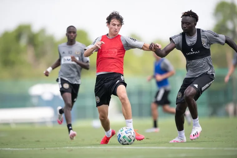 Union midfielder Brenden Aaronson (center) tries to keep the ball away from defender Olivier Mbaizo (right) during a practice session on Sunday.