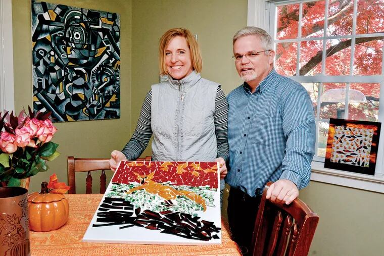 Marie and Ed Higgins display a mosaic she is working on. The painting on the wall is by their daughter, Rebecca.