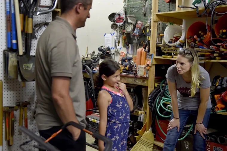 Julie Shimborski (right), interim part-time executive director at the West Philadelphia Tool Library, helps Dan Driskell and his 8-year-old daughter Stella. They are re-doing the wood floors at their home in Bella Vista.