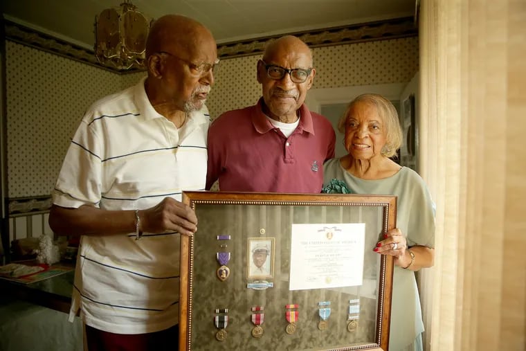 Harry Robinson, 86, left, Wallace Robinson, 81, and Mary Robinson, 84, right, hold up a tribute to their brother Joseph Robinson in Elkins Park, PA on June 18, 2018. Cpl. Joseph Robinson died a prisoner of war in North Korea in 1951.