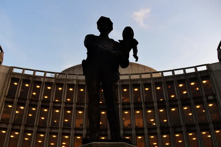 A statue depicting a police officer holding a small child sits outside the Philadelphia Police Administration Building at Race and Arch Streets.