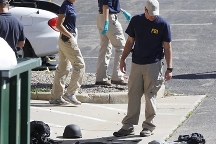 Investigators check evidence outside the Colorado theater where a man killed 12 and wounded 59. (DAVID ZALUBOWSKI / AP)