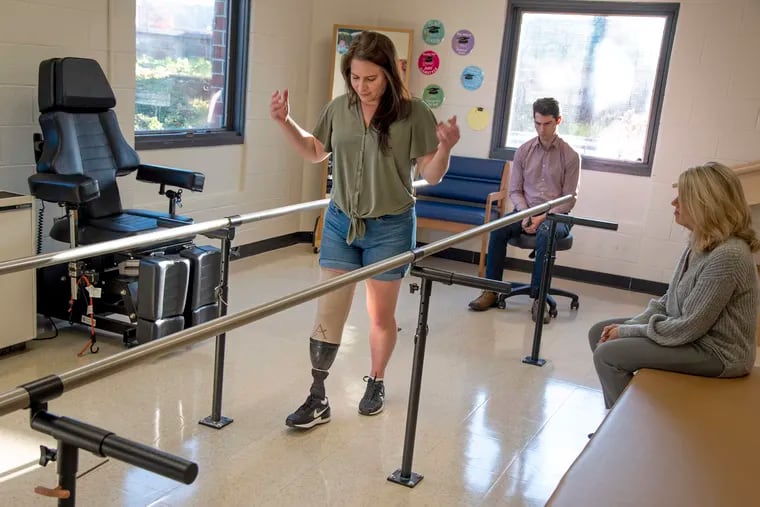 Maria Pagnotta visits the office of Chris Mullin (rear) at MedEast Post-Op & Surgical offices in Ambler. He watched her walk and made adjustments to her prosthesis on Nov. 15.