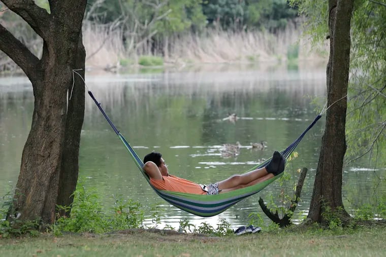 A person rests on a portable hammock near the lakes at FDR Parks in South Philadelphia on Monday, August 9, 2021.