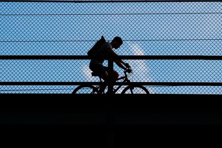 An unidentified man rides his bike along the Girard Avenue bridge during a hot humid day in Philadelphia, Pa. Wednesday, September 15, 2021.