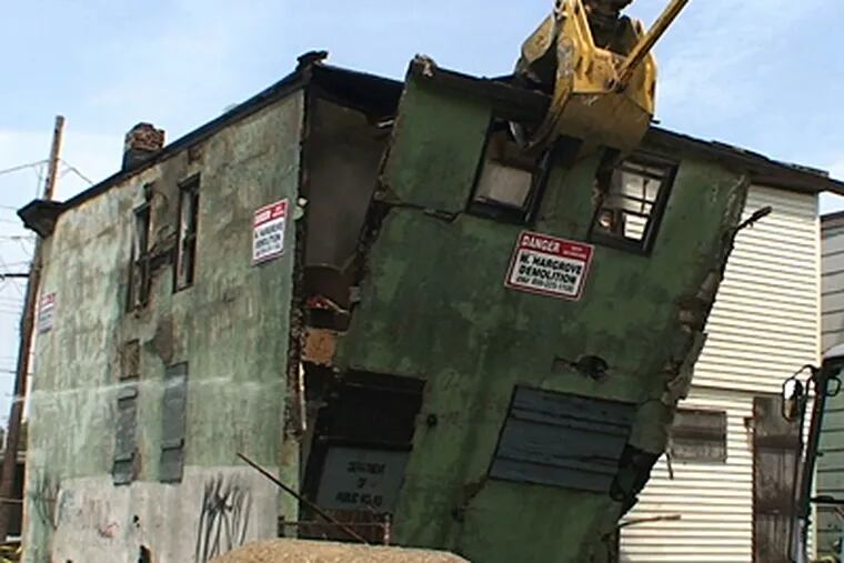 An abandoned house is torn down on Marlton Ave in Camden, part of a project in which 80 unsafe and abandoned buildings will be demolished. (Ron Tarver/Inquirer)