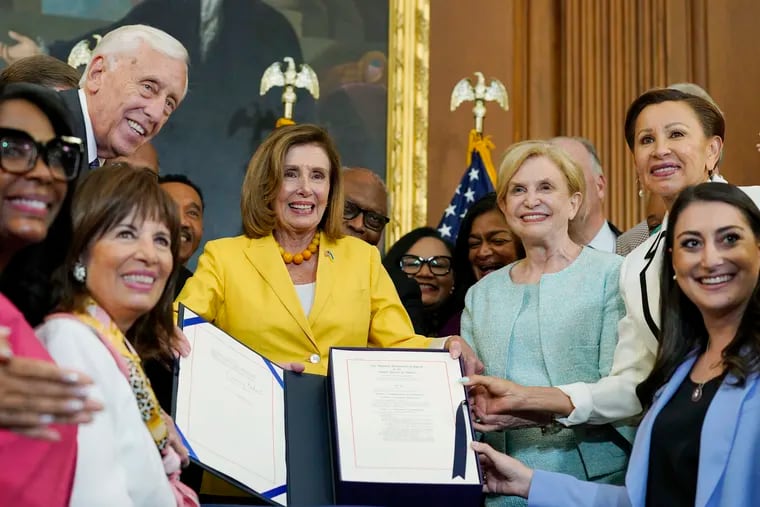 House Speaker Nancy Pelosi of Calif., surrounded by House Democrats, stands up after signing the Inflation Reduction Act of 2022 during a bill enrollment ceremony on Capitol Hill in Washington, Friday, Aug. 12, 2022.