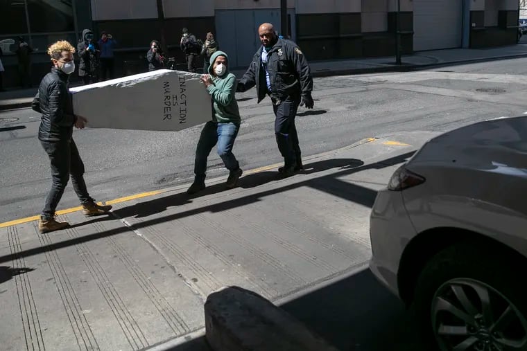 Sameer Khetan, right, and Cara Tratner carry a coffin outside Juanita Kidd Stout Center for Criminal Justice in Philadelphia on Wednesday. The protesters were there to demand the release of more inmates in city jails due to coronavirus fears. Yesterday Mayor Jim Kenney announced the first death from COVID-19 in the Philadelphia jails.