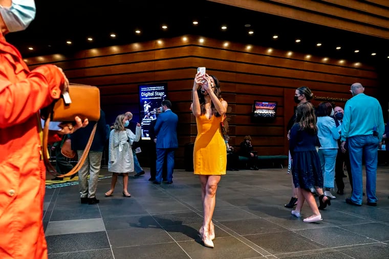 Julia Vu of Northern Liberties pauses to take a photo as.she arrives with other audience members in the lobby of  the Kimmel Center Oct. 5, 2021, on opening night for the Philadelphia Orchestra at Verizon Hall.