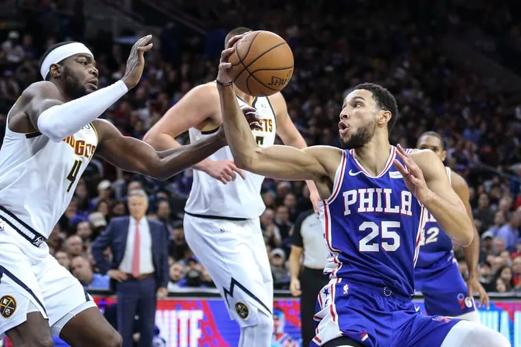 The Sixers' Ben Simmons grabbing a loose ball in front of the Nuggets' Paul Millsap (left) in December 2019.