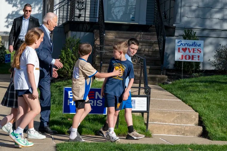 Accompanied by school children, President Joe Biden leaves after a visit to his childhood home in Scranton on Tuesday.