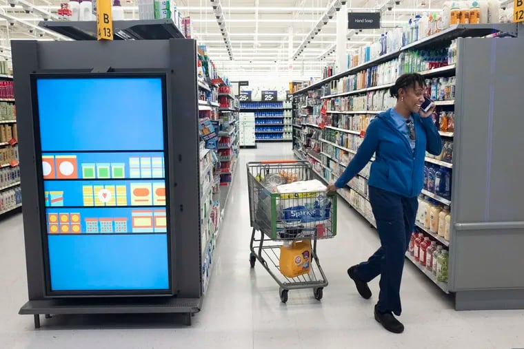 A customer pulls her shopping cart past an information kiosk at a Walmart Neighborhood Market, Wednesday, April 24, 2019, in Levittown, N.Y. Kiosks and signs throughout the store keep customers informed that they are shopping in an artificial intelligence factory. Technological change like the advancement of AI upends social life and makes business as usual impossible, writes Temple's Devon Powers.