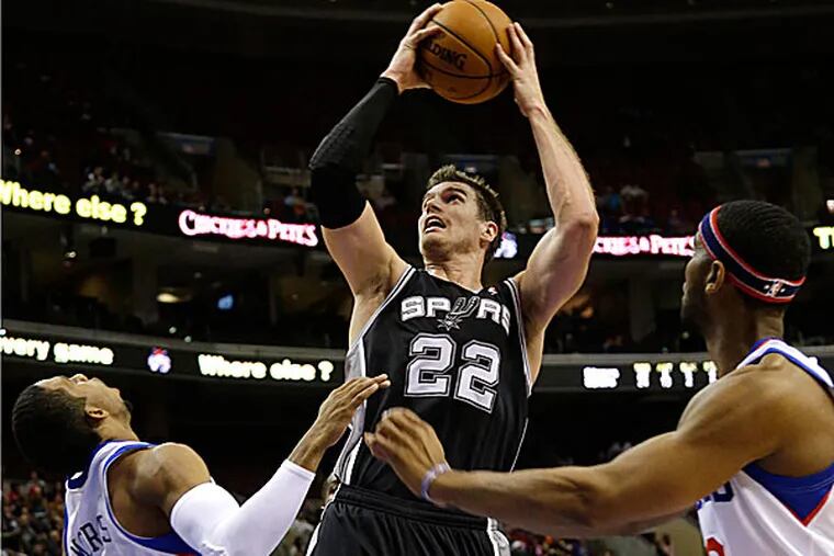 The Spurs' Tiago Splitter goes up for a shot as the 76ers' Darius Morris and Brandon Davies defend during the first half. (Matt Slocum/AP)