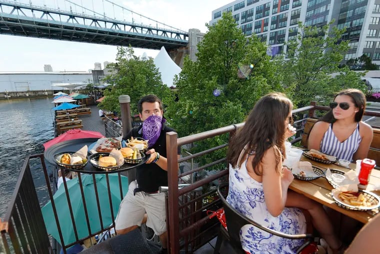 At Morgan’s Pier on the Delaware River, server Tyler McCusker carries a food order up the spiral staircase to the area known as the crows nest on June 12, 2020. Outdoor dining is now allowed as Philadelphia moves into the yellow phase of the re-opening due to the coronavirus (COVID-19) pandemic.
