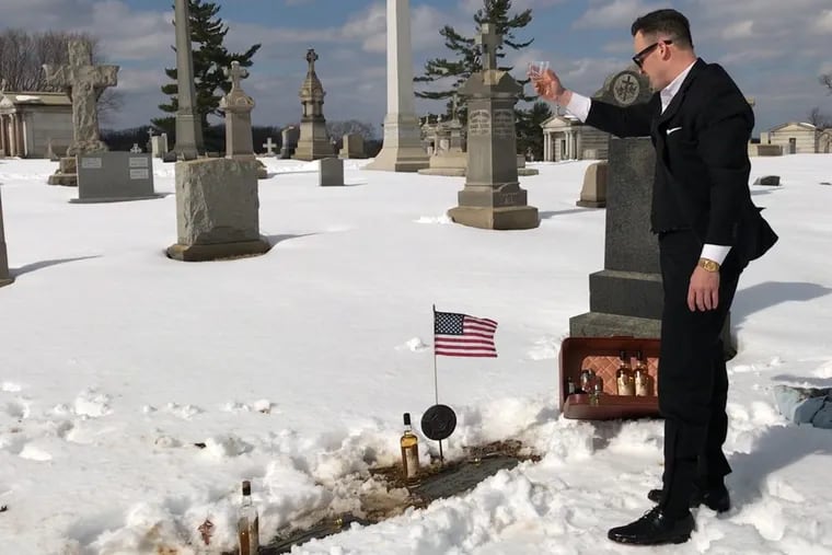 Jason Fogg, with a bottle of Irish whiskey named after his great grandfather, toasts his ancestor's memory at Holy Sepulchre Cemetery in Philadelphia