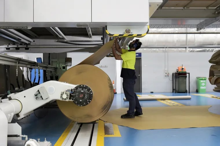 An employee loads a roll of paper onto a cardboard pressing machine at a factory in Australia this year. International Paper plans to open a factory in Atglen, Pa., in 2023 to manufactured corrugated paper.