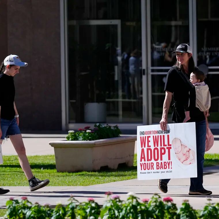 Pro-life demonstrators walk in the front of the Arizona Capitol prior to the vote on the proposed repeal of the state's near-total ban on abortions prior to winning approval from the state House in Phoenix.