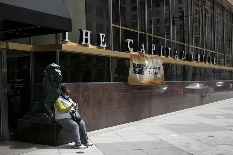 A woman rests on the lion statue outside of the Capital Grille in Center City Philadelphia.