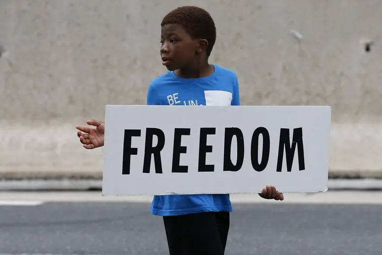 Alonzo Jackson, 7, of the Third Antioch Dance Academy holds a sign representing the Juneteenth Parade, recognizing the end of slavery in America, along East Market Street on Saturday, June 23, 2018.