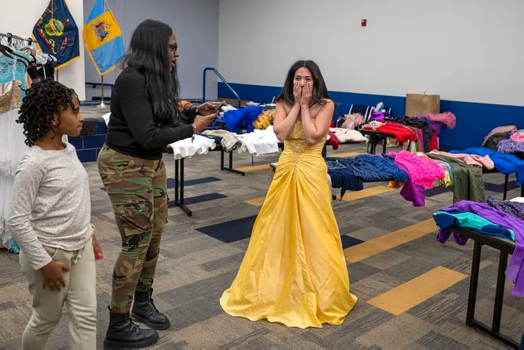 Police Officer Roslyn Talley, with her granddaughter Karina Coleman, 10, photographs Marisol Olivero (right) as she tries on a dress at the Philadelphia Police Training Center Sunday during a dress giveaway.