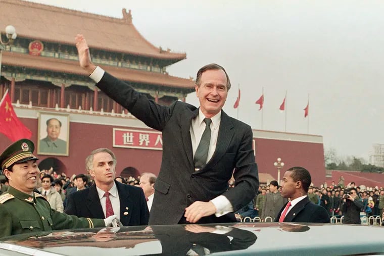 In this 1989 file photo, then-President George H.W. Bush stands on his car and waves to crowds in Tiananman Square in Beijing. Chinese state media are praising Bush this week as a "statesman of vision," recalling the late president's role in helping end the Cold War and establishing policies toward China.