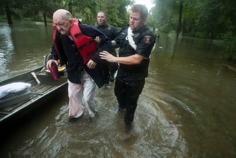 Fred Stewart (left) is helped to high ground by Splendora (Texas) police officer Mike Jones after he was rescued from his flooded neighborhood as rains from Tropical Depression Imelda inundated the area.