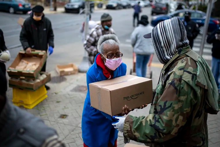 Hassan Wiggins, 63, of West Philadelphia, member of Keep It Real Ministry, hands out boxes of packaged food from Philabundance to families and residents in the area at the corner of 59th Street and Lansdowne Avenue in April.