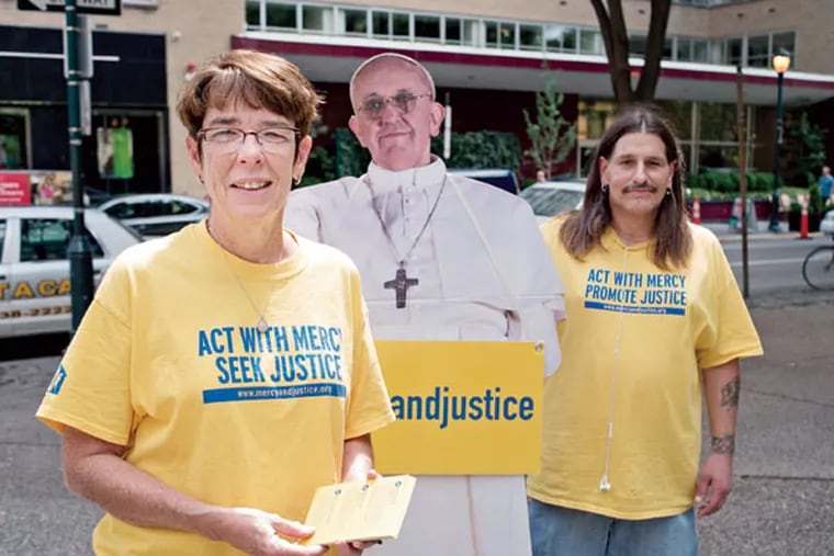 Sister Mary Scullion and Project HOME resident Rich Gessner, joined by a cutout figure of Pope Francis, work their location on Rittenhouse Square to drum up help in fighting poverty. (MATTHEW HALL / For The Inquirer)