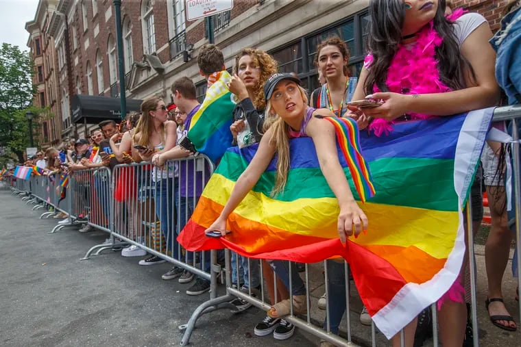 Kathryn Wilson, center, of Sicklerville, NJ, holds onto to her rainbow flag while she and the rest of the crowd wait for the 2018 Pride Parade.