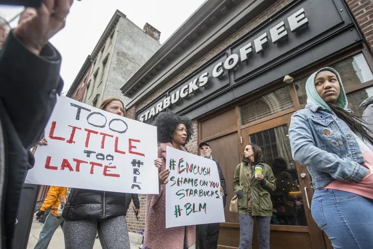 Soren McClay, left, and her stepmother, Donn T, right, hold up signs during the local Black Lives Matter demonstration at the Starbucks at 18th and Spruce Streets on Sunday.