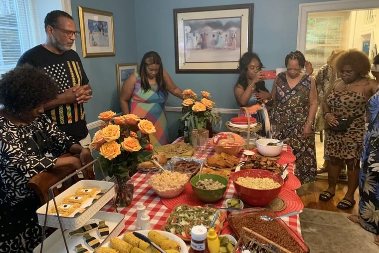 Pamela and Weller Thomas of Pathfinders Travel magazine say grace before eating during a Juneteenth celebration in their East Oak Lane home in 2021.