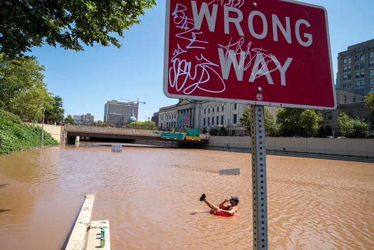 Austin Ferdock drinks a beer while floating in floodwater that continues to rise over the submerged Vine Street Expressway, Interstate 676, following a storm amid the remnants of Hurricane Ida, on September 2, 2021, in Philadelphia.