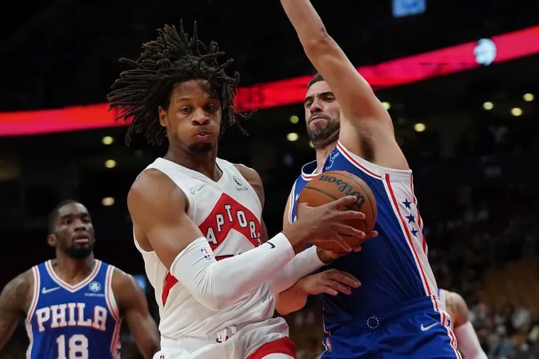 Toronto Raptors forward Freddie Gillespie , front left, and Philadelphia 76ers' Georges Niang, right, battle for the ball during first-half preseason NBA basketball action in Toronto, Monday, Oct. 4, 2021. (Nathan Denette/The Canadian Press via AP)