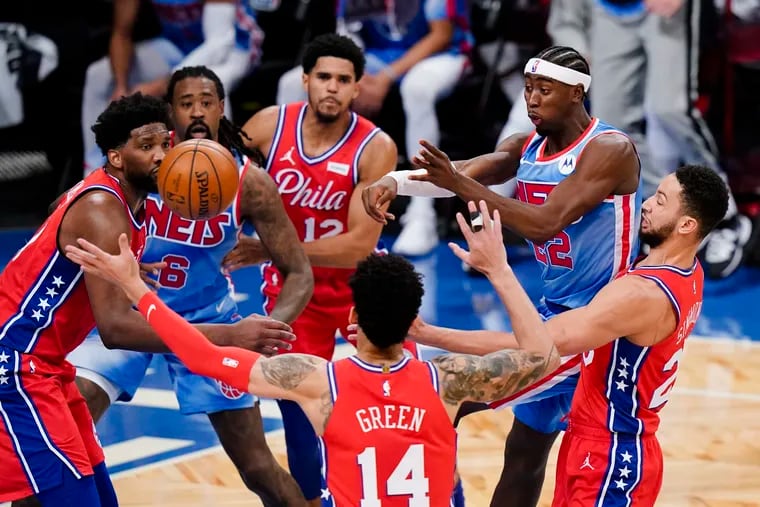 The Nets' Caris LeVert (second from right) passes away from 76ers' Danny Green (14) and Ben Simmons (right).