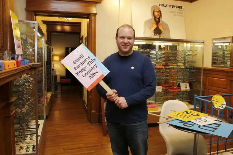 Innervision Eyewear owner Clifton Balter stands in his Center City 2nd floor showroom with a sign promoting small local business on Wednesday, January 25, 2017.