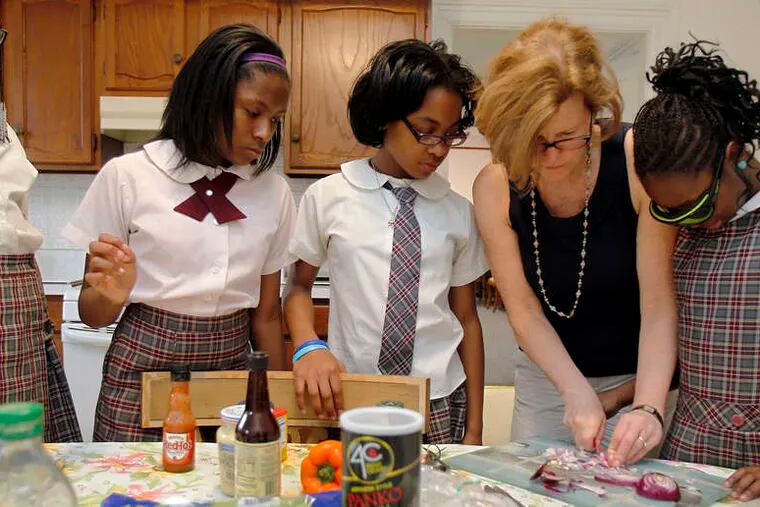 Food editor Maureen Fitzgerald reviews dicing with (from left) Chamya Davis, Hope Wescott, Kayla Reid, and Maliyah Gregg at the St. Martin De Porres convent kitchen.