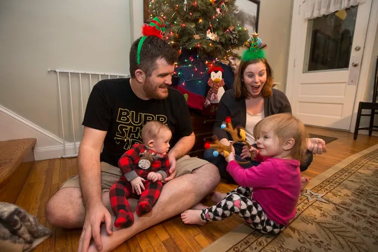 Holidays can cause childcare struggles as working parents balance festive activities and job responsibilities. Megan Vargha has to work her job over the holidays and gets pictures sent to her from her husband, Josh Vargha, a Philadelphia teacher, of him and their kids. L-R: Josh, Sam, 4 months, Megan, Maggie, 18 months, by the Christmas tree on Dec. 21, 2018.