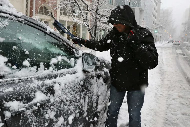 A man cleans the snow off of his car on the 800 block of Walnut Street during a winter storm, in Philadelphia, Wednesday, March 7, 2018.