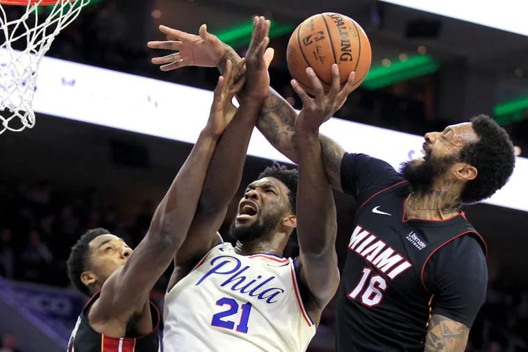 Joel Embiid, center, of the Sixers gets fouled by James Johnson, right, of the Heat during the 1st half of their game at the Wells Fargo Center on Feb. 2, 2018.