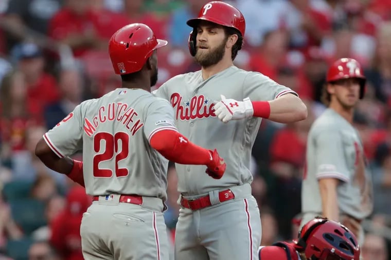 Philadelphia Phillies' Bryce Harper celebrates with Andrew McCutchen, as St. Louis Cardinals catcher Yadier Molina cleans off the plate, after Harper hit a grand slam during the second inning of a baseball game, Tuesday, May 7, 2019, in St. Louis. (AP Photo/Tom Gannam)