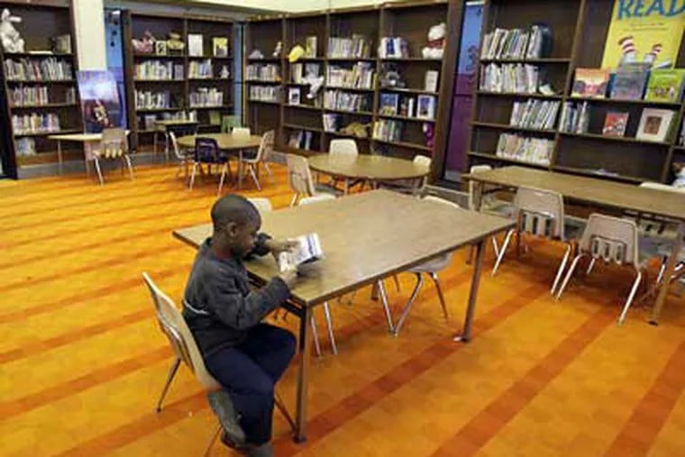Rawle Williams, 7, a first-grader at the Richard R. Wright Elementary School, spends a few minutes in the school's unstaffed library.  (Elizabeth Robertson / Staff Photographer)