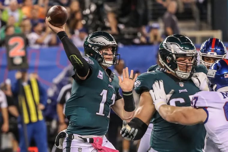 As Eagles quarterback Carson Wentz, left, steps up to pass the ball Eagles tackle Lane Johson, right, keeps a Giant defender at bay so Wentz can have time to throw in Thursdays game against the Giants on October 11, 2018. MICHAEL BRYANT / Staff Photographer