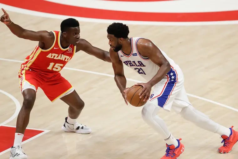 Sixers center Joel Embiid dribbles the basketball against Atlanta Hawks center Clint Capela in Game 3 of the NBA Eastern Conference playoff semifinals on Friday, June 11, 2021 in Atlanta.