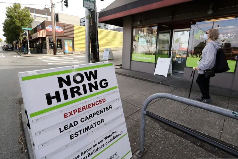 In this photo taken Thursday, June 4, 2020, a pedestrian wearing a mask walks past reader board advertising a job opening for a remodeling company, in Seattle. The U.S. unemployment rate fell to 13.3% in May, and 2.5 million jobs were added — but  the rate was underestimated by 3 points due to the way the numbers were collected. (AP Photo/Elaine Thompson)
