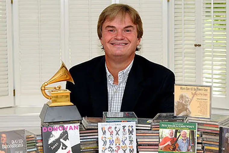 Jim Musselman, of Appleseed Recordings, sits with many of the CDs he has produced for musicians. (Photo: Tom Kelly IV / For the Inquirer)