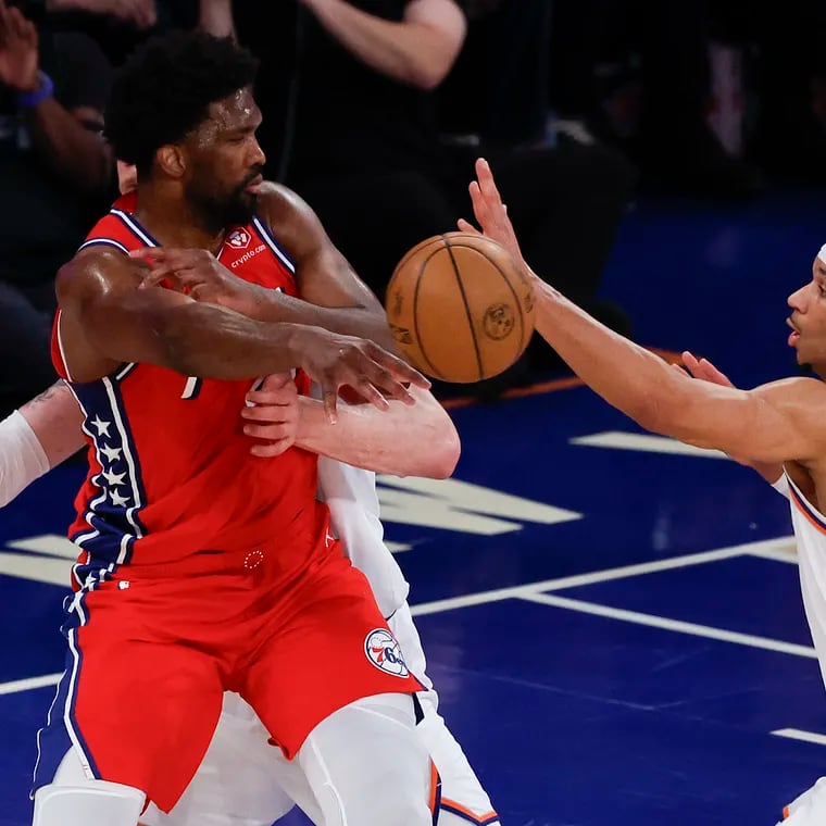Sixers center Joel Embiid passes the basketball past Knicks guard Josh Hart (right) and center Isaiah Hartenstein during the first quarter.